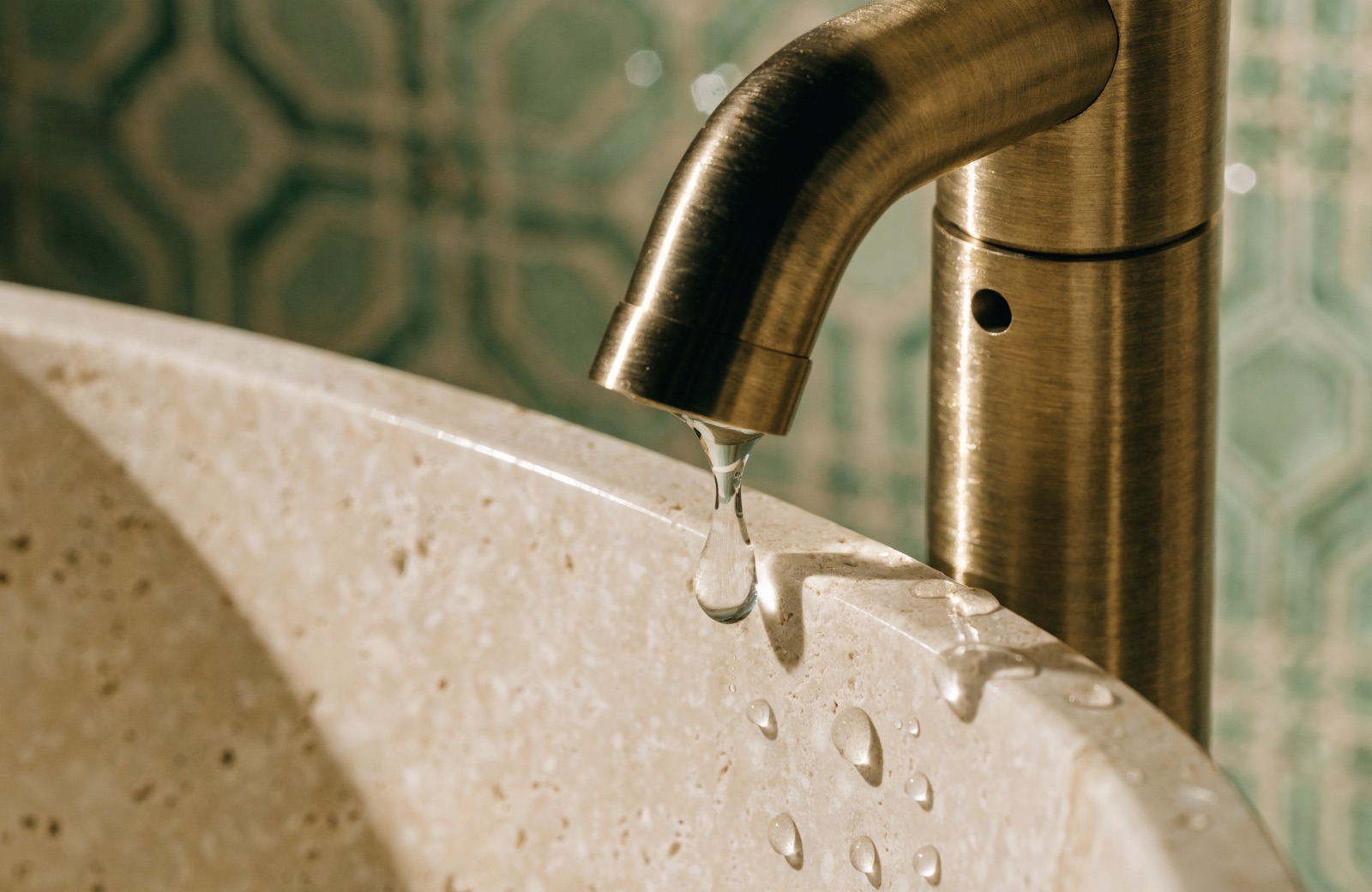 Détail de robinetterie laiton brossé posée lors d'une rénovation de salle de bain haut de gamme